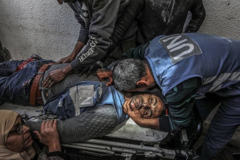 Palestinians mourn over the body of a UN staff who was killed in an Israeli air strike near a warehouse of the United Nations Relief and Works Agency for Palestine Refugees (UNRWA), at Al-Najjar Hospital in Rafah, southern Gaza Strip. Abed Rahim Khatib/dpa