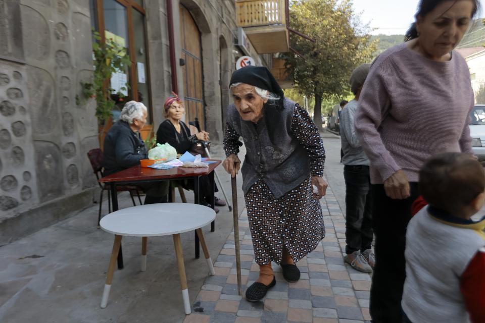 An ethnic Armenian woman from Nagorno-Karabakh walks past a street cafe after arriving to Armenia's Goris in Syunik region, Armenia, Friday, Sept. 29, 2023. Armenian officials say more than 70% of Nagorno-Karabakh's original population have fled the region for Armenia. (AP Photo/Vasily Krestyaninov)