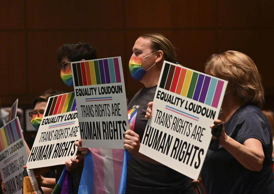 People wearing rainbow-printed face masks hold signs reading: Equality Loudoun, trans rights are human rights.