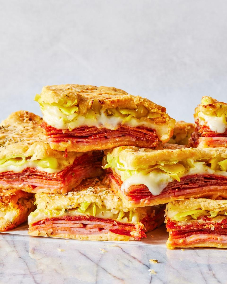 stacked sandwiches with layers of ham, pepperoni, cheese, and pepperoncinis between crescent dough