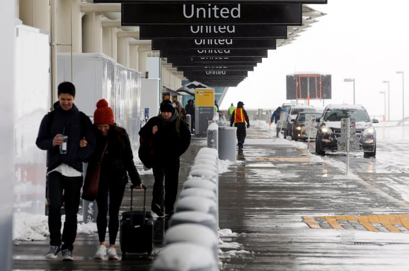 Travelers walk past the United check-in area after a snowstorm at Denver International Airport
