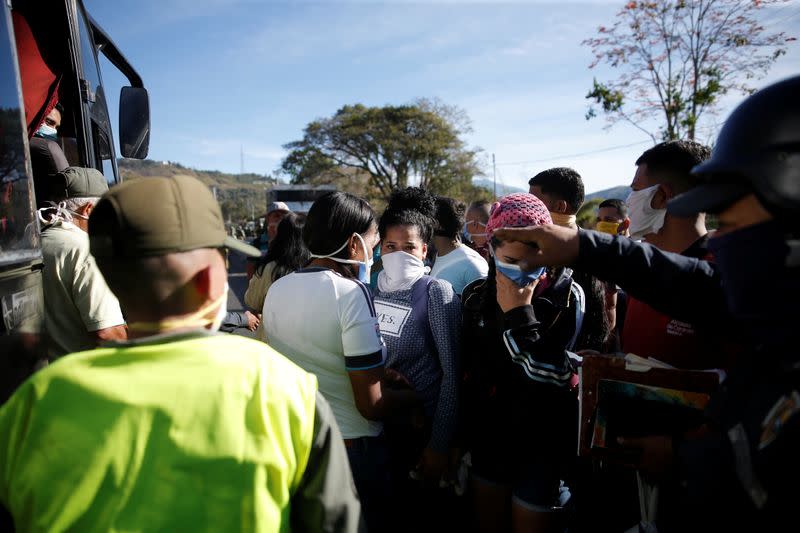 People wearing protective masks are asked by officers of the Bolivarian National Police to leave a bus at a checkpoint after the start of quarantine in response to the spreading of coronavirus disease (COVID-19) in Caracas