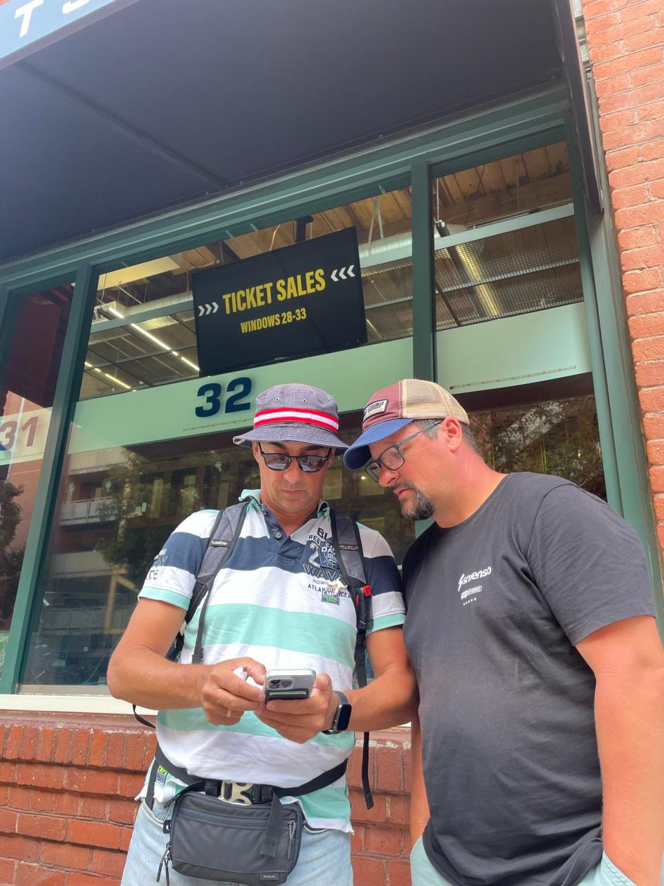 Marcus Dihlmann, left, and Marco De Tullio look at Dihlmann's smartphone after he purchased electronic tickets from the San Diego Padres ticket office in late August.