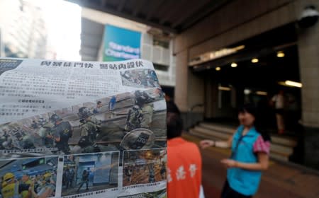 People take newspapers, with headlines and photos showing clashes between police and protesters on its front pages, in front of Wan Chai metro station in Hong Kong