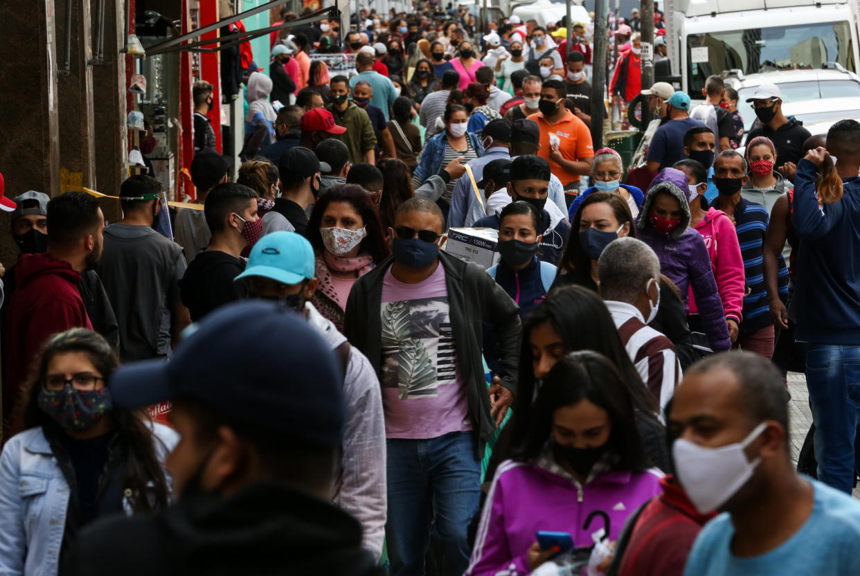 SAO PAULO, BRAZIL - JUNE 29: Shoppers wearing face masks walk in a crowded street in downtown amidst the coronavirus (COVID-19) pandemic on June 29, 2020 in Sao Paulo, Brazil. The city of Sao Paulo moves to the Yellow phase of quarantine easing, in which commercial establishments can operate following distance rules such as reduced opening hours, restricting the flow of people and maintaining hygiene standards. (Photo by Alexandre Schneider/Getty Images)