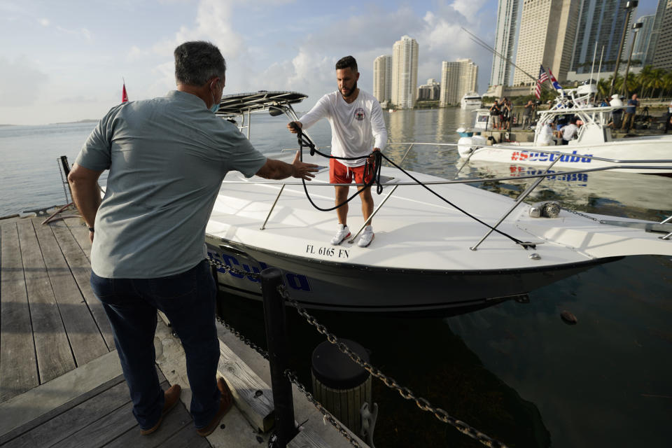 Ramon Saul Sanchez, left, leader of the nonprofit group Movimiento Democracia that launched several flotillas in the past, helps boater Julio Gonzalez tie up his boat, Friday, July 23, 2021, in downtown Miami. A small group of Cuban Americans launched motorboats from Miami to their homeland to show support for people experiencing hardships on the island. Five boats left the Bayside marina just before 8 a.m. Friday. They plan to refuel in Key West before heading into the Florida Straits. (AP Photo/Wilfredo Lee)