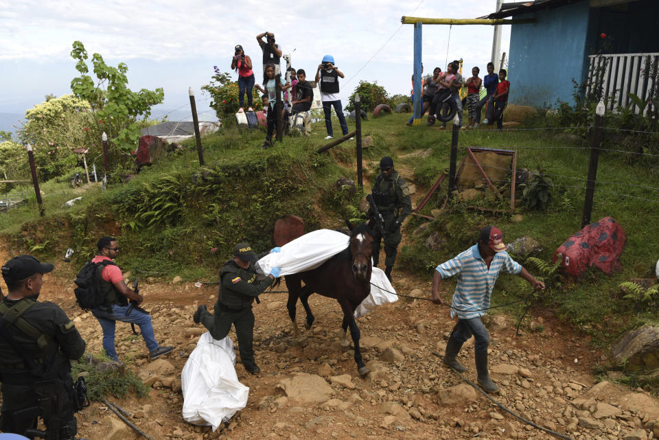 A police officer helps transport the body of one of at least five people killed during a skirmish between illegal armed groups in Jamundi, southwest Colombia, Friday, Jan. 17, 2020. Authorities say rebels with the former Revolutionary Armed Forces of Colombia operate in the area and may have been involved. (AP Photo/Christian EscobarMora)