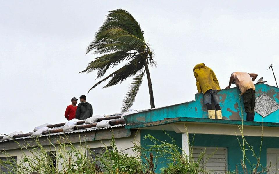 Cubans repair a roof in San Juan y Martinez, Pinar del Rio Province, on September 27, 2022 after the passage of Hurricane Ian. - Powerful Hurricane Ian left a trail of destruction after battering western Cuba on Tuesday, while Florida battened down in preparation for a dangerous direct hit as the strengthening storm churns north.