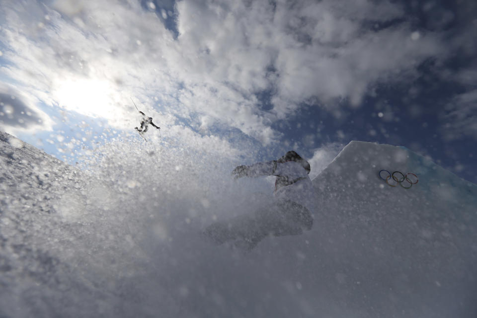 A competitor takes a jump as a team member follows during freestyle skiing slopestyle training at the 2014 Winter Olympics, Monday, Feb. 10, 2014, in Krasnaya Polyana, Russia.