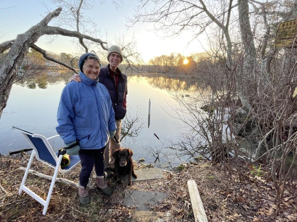 Jane Ward and her husband Steve Waller, of Centerville, are among citizen scientist volunteers who count herring, and collect other relevant data when the fish make their springtime return  from the ocean to the pond of their birth to spawn. There is a herring run next to their property on Long Pond. They are pictured here at their observation station with their dog, Rosie.