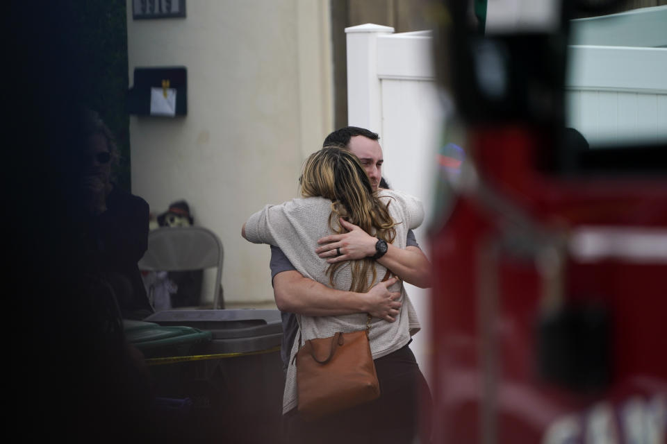 Two people react at the scene of a plane crash in a neighborhood Monday, Oct. 11, 2021, in Santee, Calif. Authorities say at least two people were killed and two others were injured when a small plane crashed into the suburban Southern California neighborhood, setting two homes ablaze. (AP Photo/Gregory Bull)