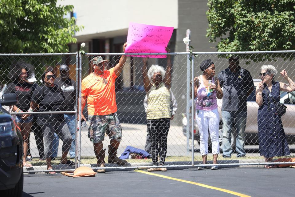 Cariol Horn gets help holding the sign, "You want us to shop here, yet you have a gate keeping us out now!" A fence with security did not allow people to wander into the event.