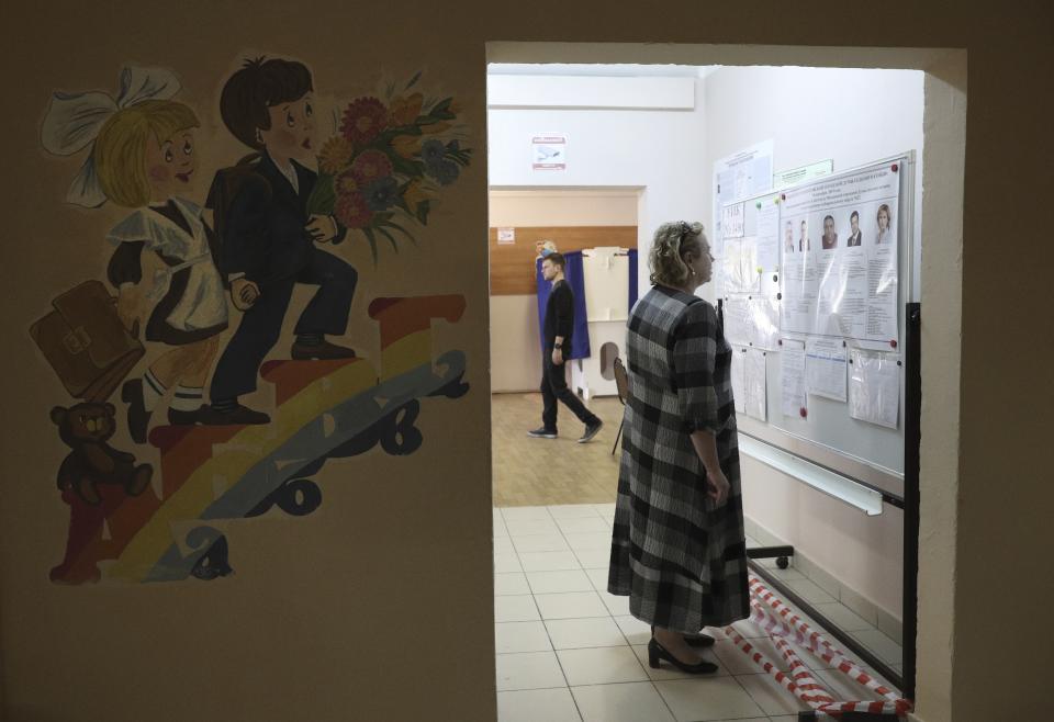 A woman reads pre-election leaflets at a polling station during a city council election in Moscow, Russia, Sunday, Sept. 8, 2019. Residents of Russia's capital are voting in a city council election that is shadowed by a wave of protests that saw the biggest demonstrator turnout in seven years and a notably violent police response. (AP Photo/Andrew Lubimov)