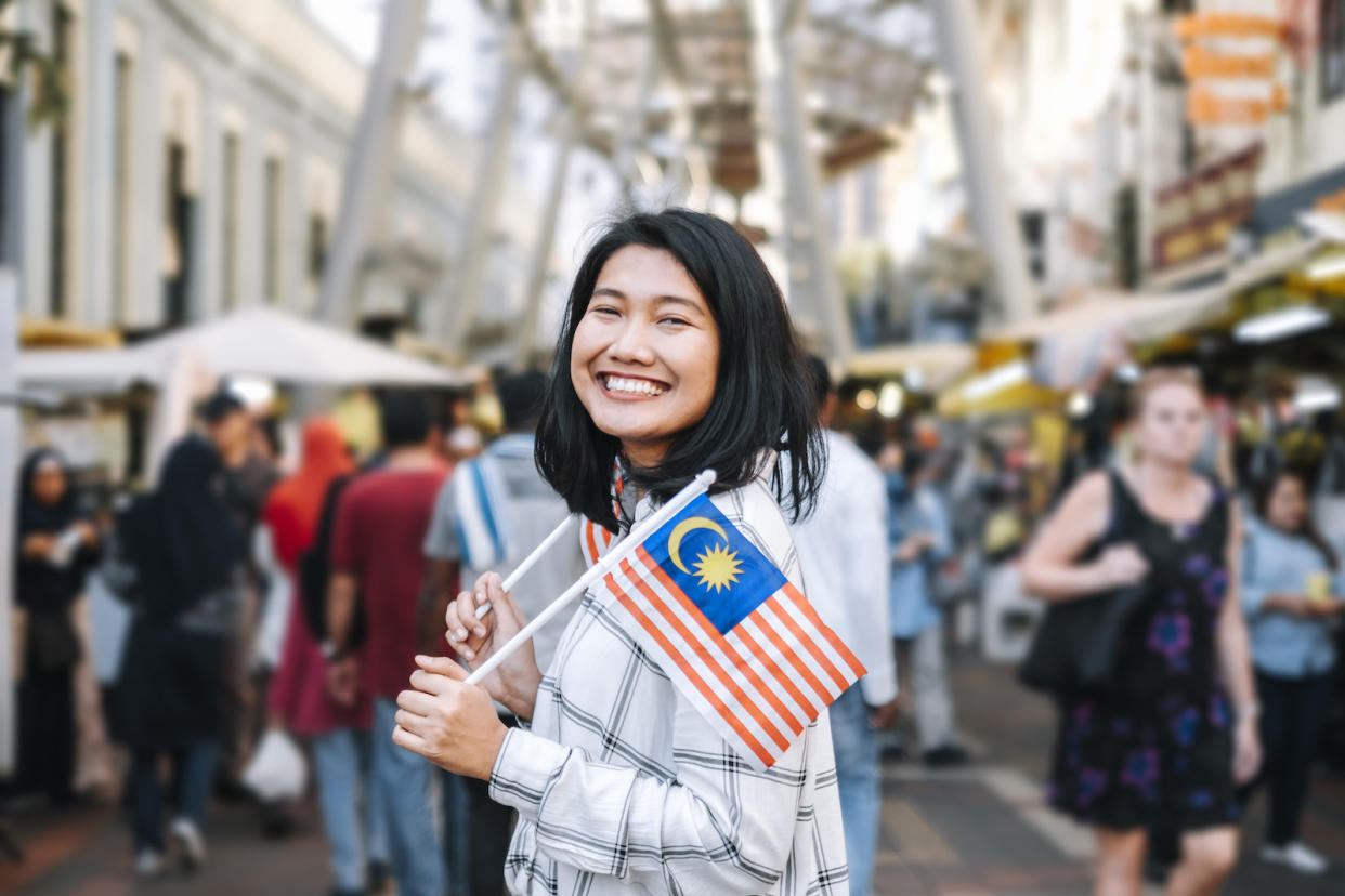A Malaysian woman on a street carrying the country's flag as Malaysia's 66th Merdeka Day approaches.