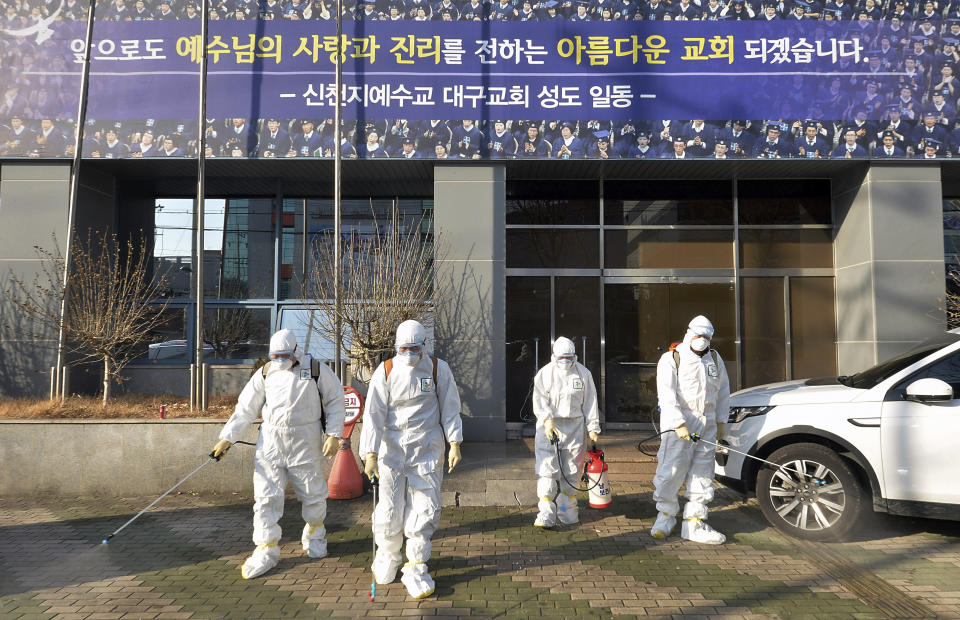 In this Wednesday, Feb. 19, 2020, photo, workers wearing protective gears spray disinfectant against the coronavirus in front of a church in Daegu, South Korea. The mayor of the South Korean city of Daegu urged its 2.5 million people on Thursday, Feb. 20, to refrain from going outside as cases of a new virus spike. (Lee Moo-ryul/Newsis via AP)