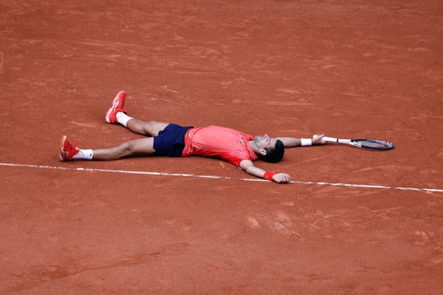 Novak Djokovic lies on the clay after Casper Ruud's final shot flies wide