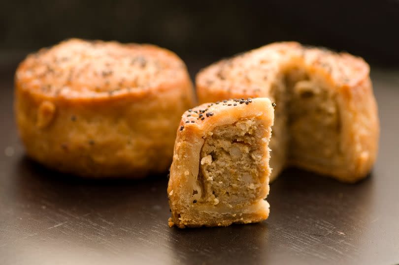 A slice of pork pie with pork pies in background