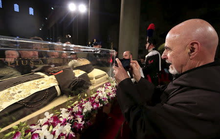 A friar takes a picture at the exhumed body of the mystic saint Padre Pio in the Catholic church of San Lorenzo fuori le Mura in Rome, February 3, 2016. REUTERS/Yara Nardi