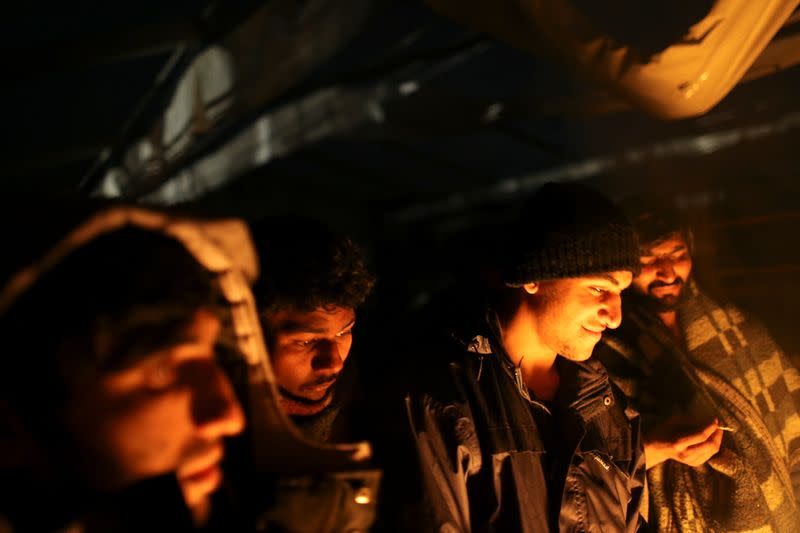 Migrants warm up around a fire at camp "Lipa" after it was closed, in Bihac