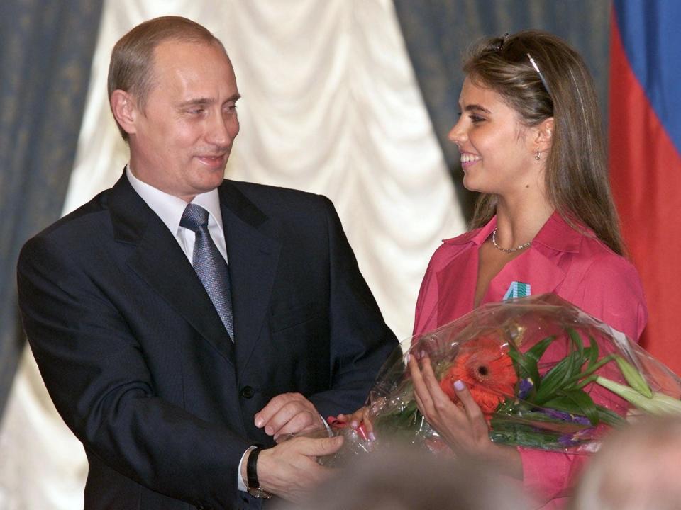 Russian President Vladimir Putin (L) hands flowers to Alina Kabayeva, Russian rhytmic gymnastics star and Olympic prize winner, after awarding her with an Order of Friendship during annual award ceremony in the Kremlin 08 June 2001.
