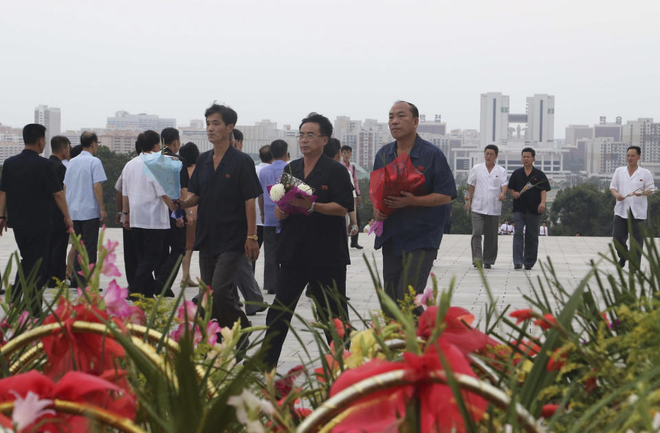 Visitors carry flowers to the statues of President Kim Il Sung and Chairman Kim Jong Il on Mansu Hill to commemorate the 77th anniversary of Korea's Liberation in Pyongyang, North Korea, Monday, Aug. 15, 2022. (AP Photo/Jon Chol Jin)