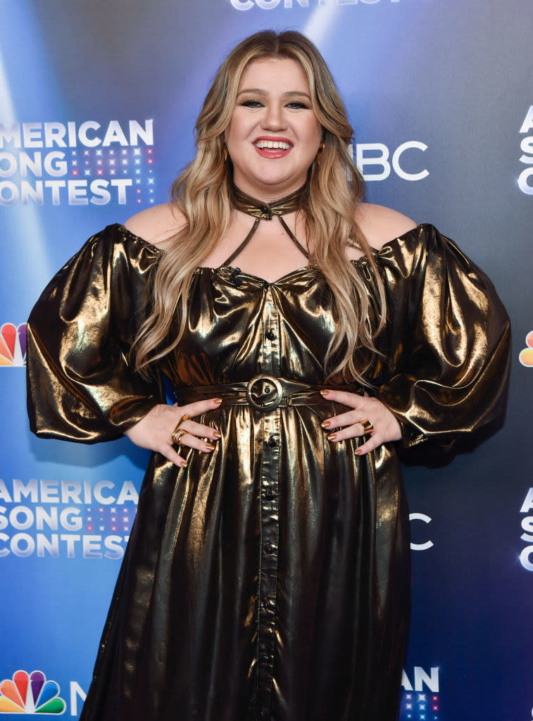 Kelly Clarkson smiling with her hands on her hips