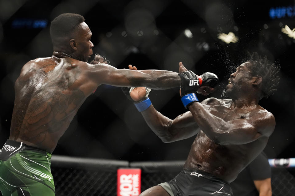 Israel Adesanya, left, hits Jared Cannonier in a middleweight title bout during the UFC 276 mixed martial arts event Saturday, July 2, 2022, in Las Vegas. (AP Photo/John Locher)