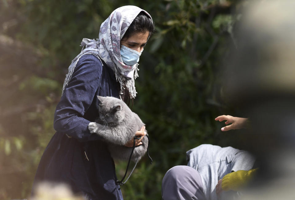 Migrant woman holds a cat as she stays an area between the borders of Belarus and Poland in the village of Usnarz Gorny, Poland, on Friday Aug. 20, 2021. A refugee rights group in Poland said Friday that 32 people who fled Afghanistan have been trapped for 12 days in an area between the Polish and Belarusian borders, caught up in a standoff between the two countries. (AP Photo/Michal Kosc)