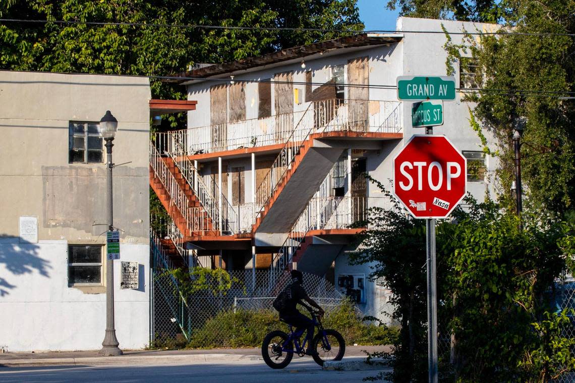 A bicyclist rides past rundown buildings near Hibiscus Street and Grand Avenue in Miami’s West Coconut Grove.