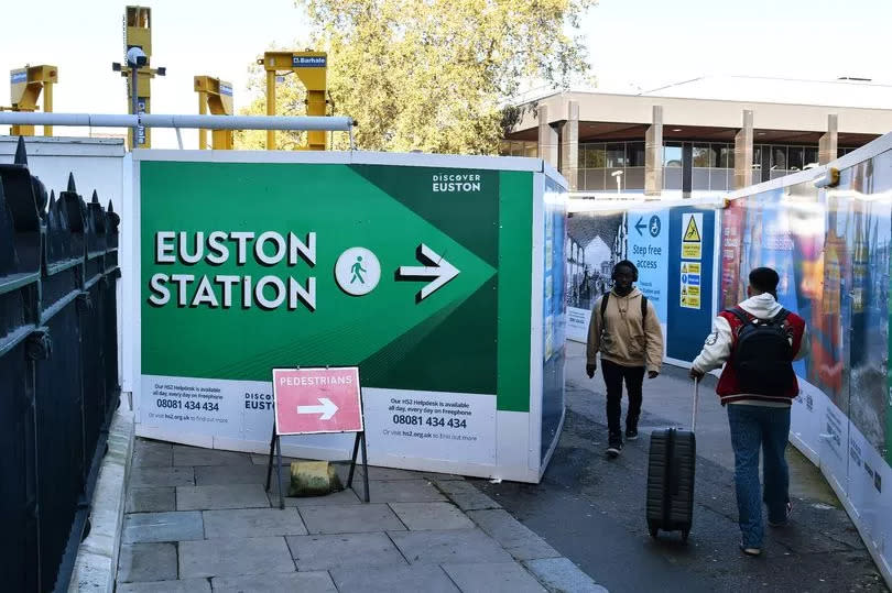 People navigate their way around hoardings surrounding the construction site for the HS2 High speed rail terminus at Euston Station on October 22, 2023 in London, England