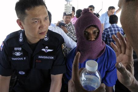 Police Major General Thatchai Pitaneelaboot (L) listens as a Rohingya trafficking victim leads a police unit to a camp where he was detained in Satun, southern Thailand March 27, 2014. REUTERS/Andrew RC Marshall