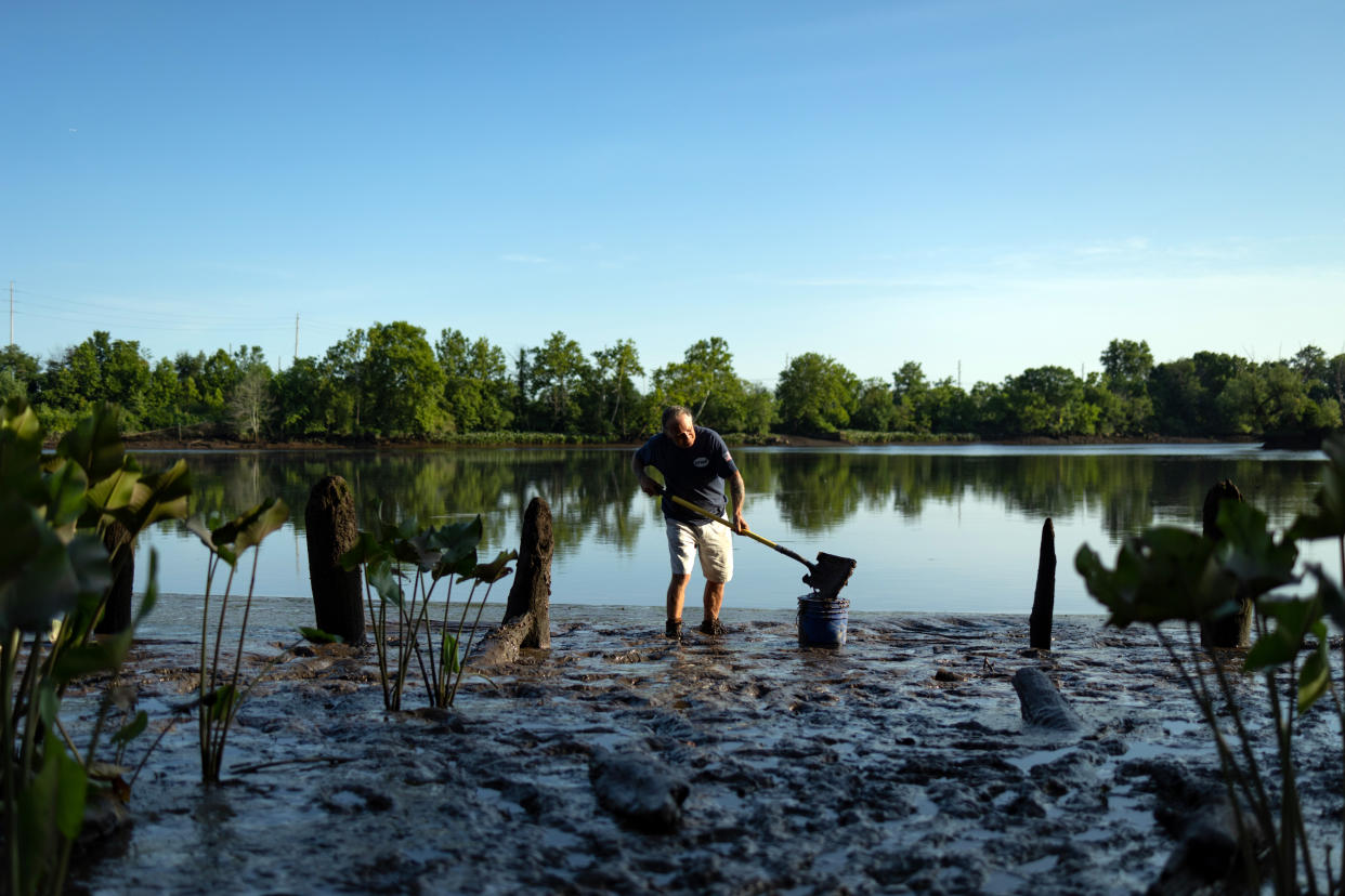 Jim Bintliff usa una pala y un cubo para recolectar barro del río Delaware, en el sur de Nueva Jersey, el domingo 24 de julio de 2022. (Hannah Beier/The New York Times)