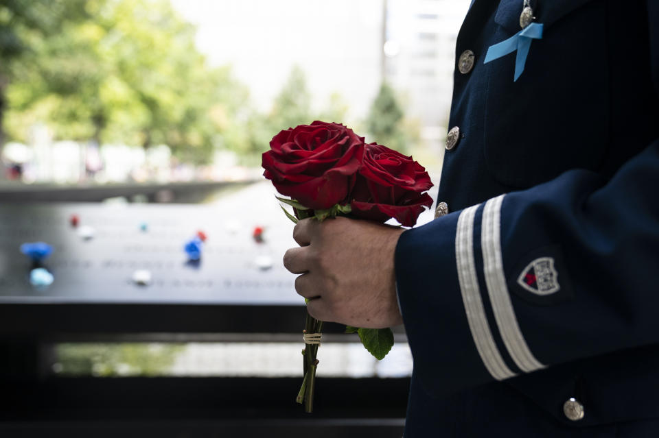 A mourner brings roses to the north pool after the conclusion of ceremonies to commemorate the 20th anniversary of the Sept. 11 terrorist attacks, Saturday, Sept. 11, 2021, at the National September 11 Memorial & Museum in New York. (AP Photo/John Minchillo)