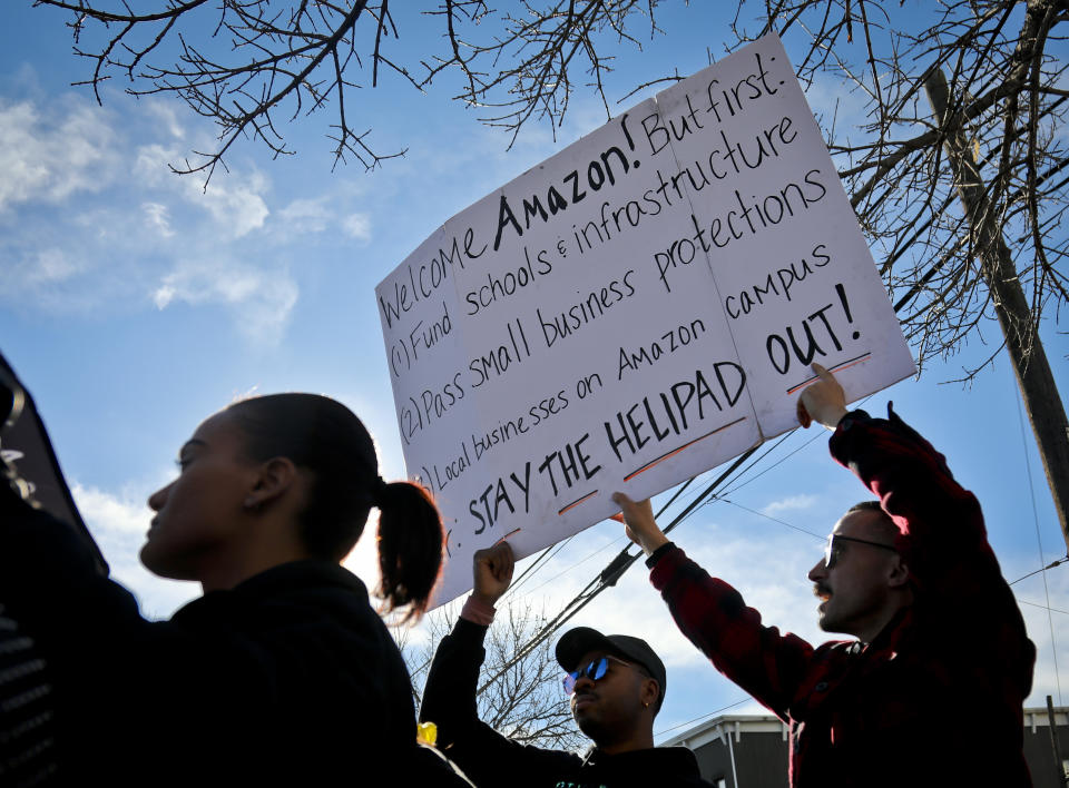 FILE - In this Nov. 14, 2018 file photo, protesters hold up anti-Amazon signs during a coalition rally and news conference opposing Amazon headquarters getting subsidies to locate in the New York neighborhood of Long Island City. Protesters had a long list of grievances to Amazon coming to their community, including the nearly $3 billion in tax incentives that New York was offering them. In its deal with the city, Amazon was promised a spot to build a helipad on or near the new offices. Some people questioned the optics of high-flying executives buzzing by a nearby low-income housing project. (AP Photo/Bebeto Matthews, File)