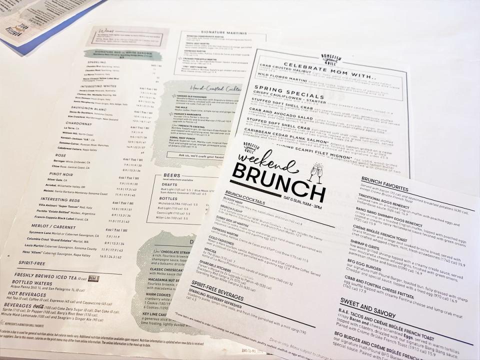 A white tablecloth with three menus for Bonefish Grill on it. One menu lists drinks, another has text reading "celebrate Mom with.." and another says "weekend brunch"