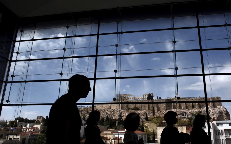 Tourists are silhouetted as they walk inside the Acropolis Museum with the Parthenon in the background  - reuters