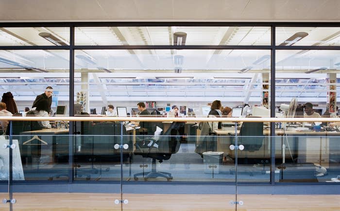 Office workspace with individuals at desks and partitions, signifying a professional environment