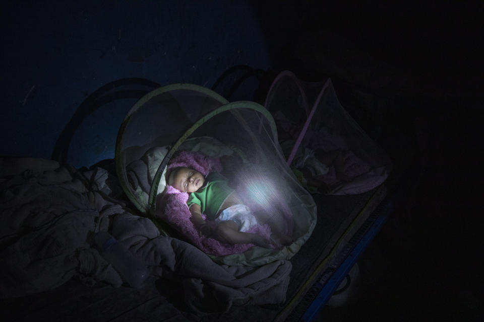 Tigrayan refugee Abraha Kinfe Gebremariam, 40, uses a flashlight to check on his 4-month-old twin daughters, Aden and Turfu, after praying at a church early in the morning, in Hamdayet, eastern Sudan, near the border with Ethiopia, on March 21, 2021. Even as Tigrayans ran for their lives or jostled for space on a boat to safety, the sight of the tall, silent, sorrowful man carrying the tiny twin girls made people pause. (AP Photo/Nariman El-Mofty)