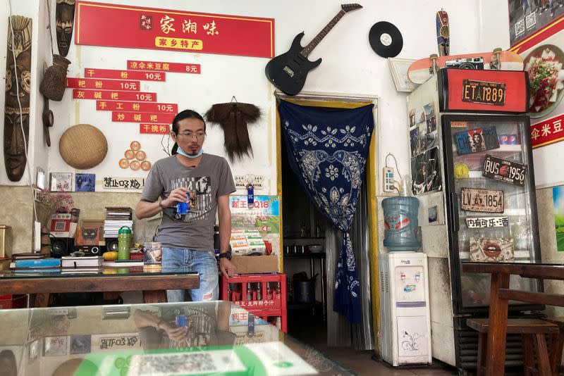 Noodles shop owner and a rock band singer Wang Zongxing stands inside his shop in Shenzhen