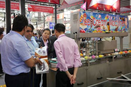 Visitors gather information in front of an ice cream machine displayed at the China Import and Export Fair in Guangzhou, China April 17, 2017. REUTERS/Venus Wu