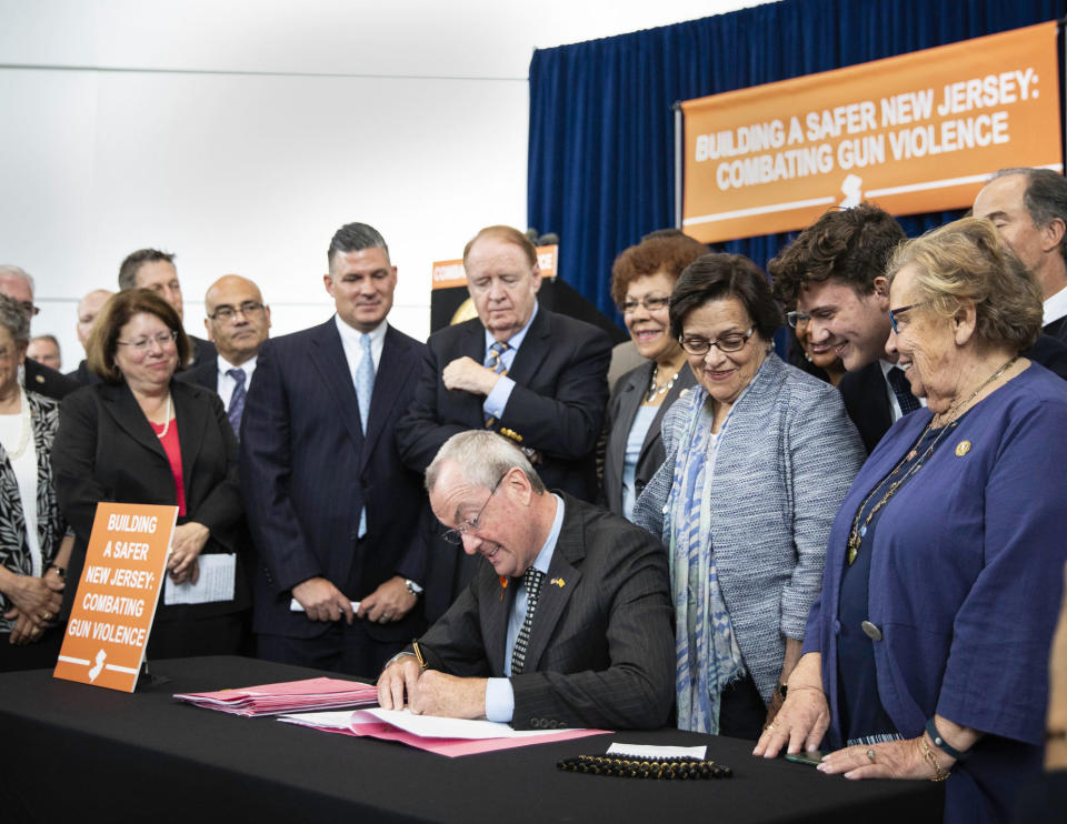 In this photo provided by the New Jersey Governor's Office, Gov. Phil Murphy, center, signs several gun safety bills at the Richard J. Hughes Justice Complex Atrium in Trenton, N.J., Wednesday, June 13 , 2018. The half-dozen new gun control laws tighten the state's already strict statutes. (Edwin J. Torres/New Jersey Governor's Office via AP)