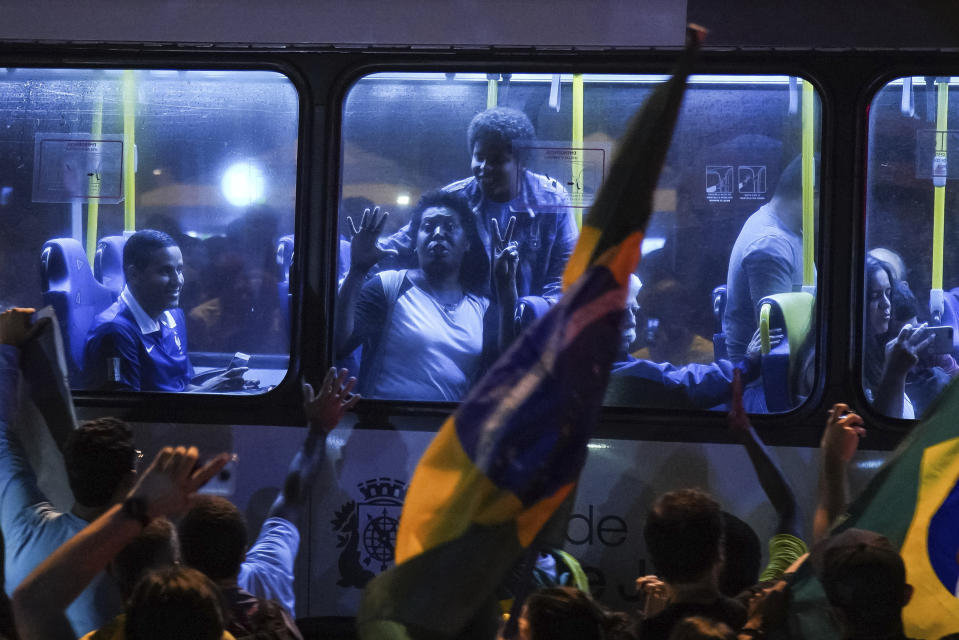 Supporters of Jair Bolsonaro, presidential candidate with the Social Liberal Party celebrate in a bus, in front of his house in Rio de Janeiro, Brazil, Sunday, Oct. 7, 2018. Official results showed that Fernando Haddad of the Workers' Party will face Jair Bolsonaro, the far-right congressman in a second-round vote. (AP Photo/Ricardo Borges)