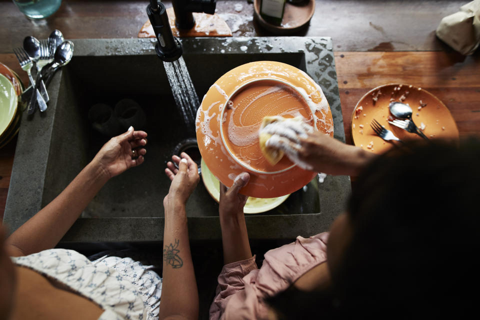 People washing dishes in a sink, seen from above