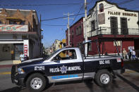 In this Feb. 10, 2020 photo, a policeman drives past town hall in Apaseo El Alto, Guanajuato state, Mexico. Part of Guanajuato's odd reality stems from its success at cracking down on crimes that impact businesses together with its inability to stop the drug gang war. In 2019, 79 police officers were killed in the state. (AP Photo/Rebecca Blackwell)