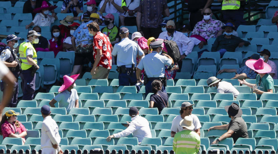 Police escort spectators from the stands during play on day four of the third cricket test between India and Australia at the Sydney Cricket Ground, Sydney, Australia, Sunday, Jan. 10, 2021. (AP Photo/Rick Rycroft)