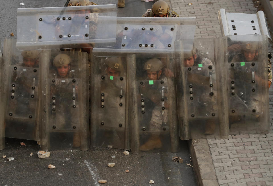 Lebanese soldiers hide from stones behind their protective shields as they clash with supporters of Prime Minister-designate Saad Hariri who stepped down on Thursday in Beirut, Lebanon, Thursday, July 15, 2021. Hariri says he is stepping down, nine months after he was named to the post by the parliament. He is citing "key differences" with the country's president, Michel Aoun. (AP Photo/Hussein Malla)