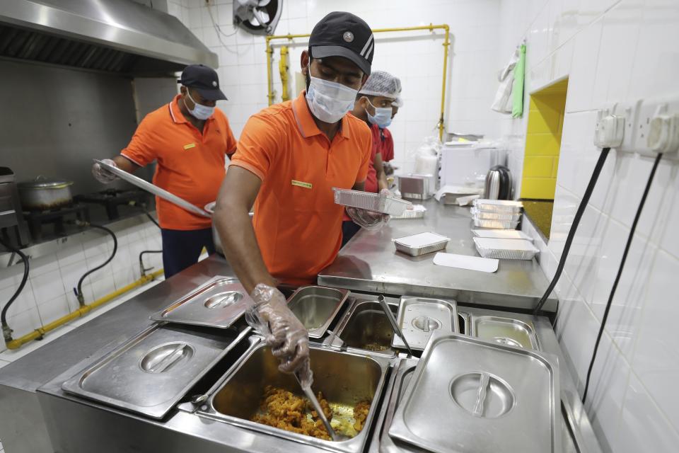 Cooks prepare free food for needy people at a restaurant in Sharjah, United Arab Emirates, Wednesday, Nov. 4, 2020. In this industrial underbelly in the suburbs of Dubai, workers methodically assemble packaged takeout meals of biryani rice, dal and brightly colored chicken curry for people in poverty and desperate to eat. (AP Photo/Kamran Jebreili)