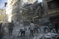 Syrian civilians and rescuers gather at the site of an air strike by government forces in the rebel held neighbourhood of Al-Shaar in Aleppo