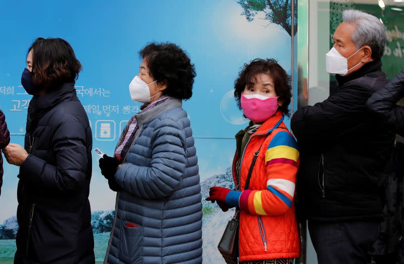 People wearing protective masks, following an outbreak of coronavirus disease (COVID-19), stand in a line to buy masks in front of a drug store in Daegu