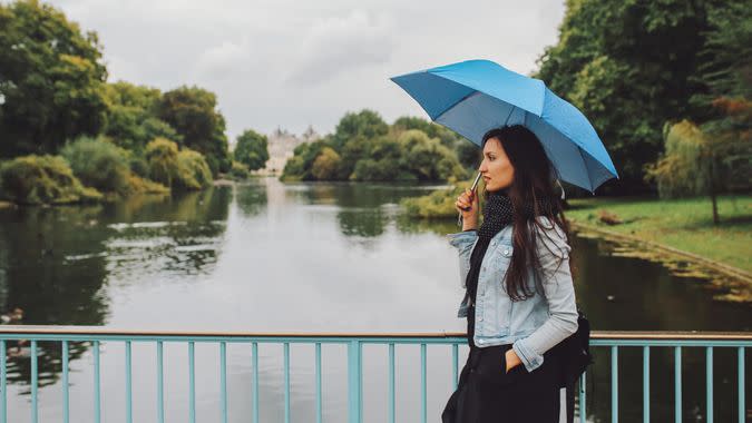 Young woman walking with umbrella in the London public park.